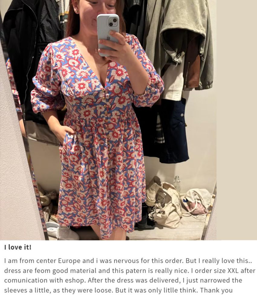 Person wearing a floral dress taking a mirror selfie in a clothing store.