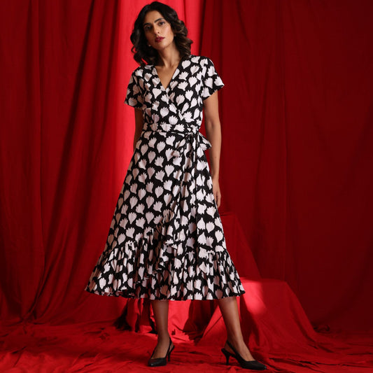 Woman wearing a black and white patterned dress against a red curtain backdrop